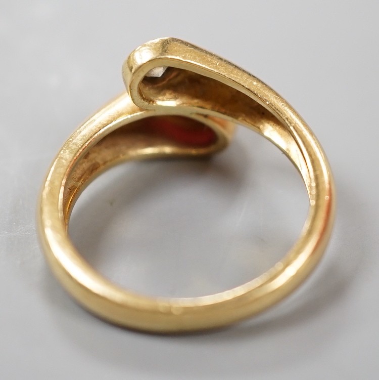 A modern 18k, cabochon ruby and round cut diamond set crossover ring, size N, gross weight 6.8 grams.